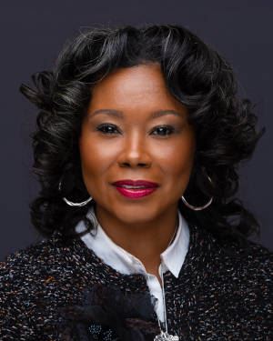 Mayor Shenise Turner-Sloss smiling in a multi-colored tweed jacket.