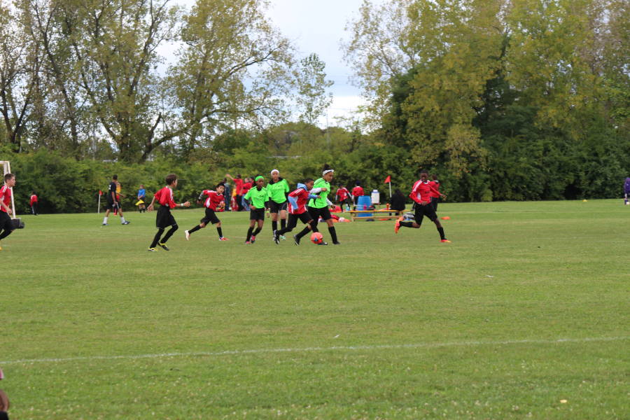Youth soccer game with players in red and green jerseys at Dayton World Soccer Games.