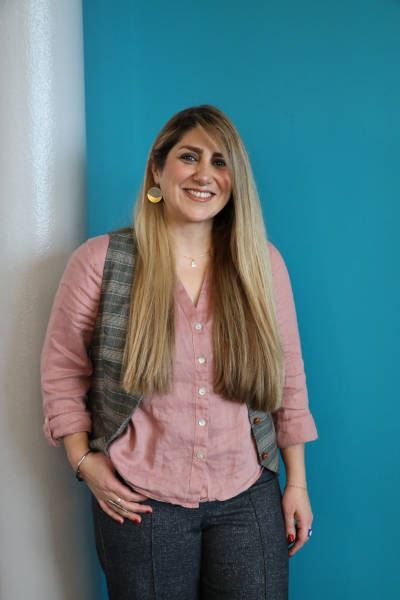 Samaneh Faramarzi posing for photo in front of turquoise painted wall.