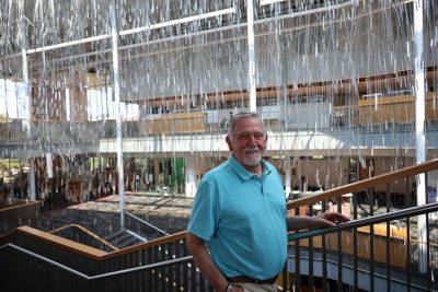 Robert Salinas posing for photo on stairwell at Dayton Metro Library with drapery of glass behind.