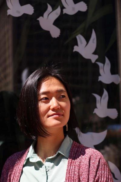 Sanghyun Lee standing in front of a window with silhouettes of white doves on it.
